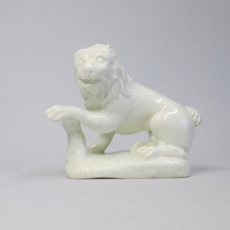 A rare Bow early "Blanc De Chine" seated Lion, left facing on an irregular rock work oblong base with it's left paw resting on a stump. Circa 1750-2