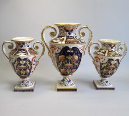 A large garniture of Bloor Derby Vases, decorated with Imari colours of iron red, blue and gold, with acanthus scroll handles and square base.  Circa 1830-35