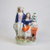 A Staffordshire figure of two children the boy "trundling" with a hoop and stick and the girl with a rabbit. Circa 1860