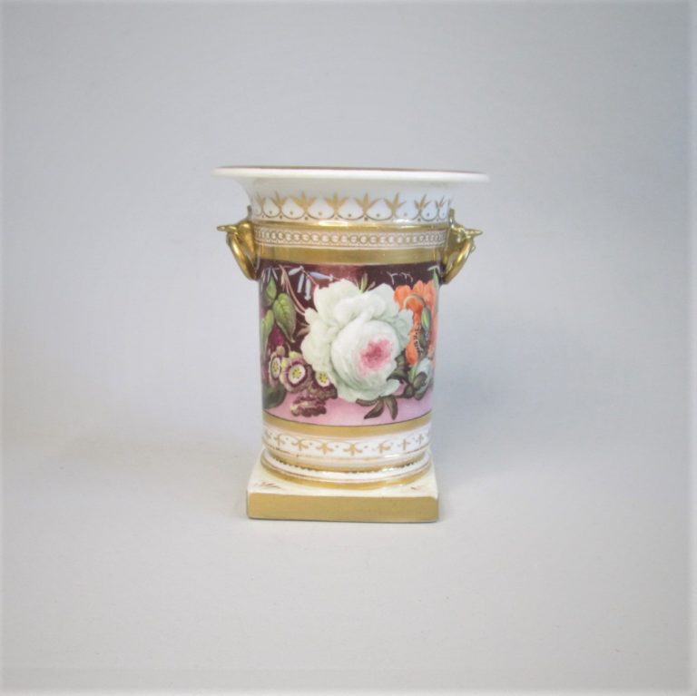 A spill vase with ring handles held in the beaks of gargoyles hand