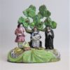 A Staffordshire pearlware 'Tythe Pig' group, depicting the farmer, holding a pig with other produce of bushels of corn and his wife holding a baby.   Circa 1820