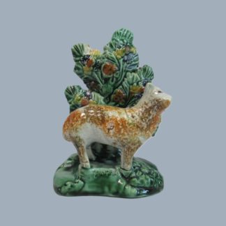 A Staffordshire lead glazed earthenware figure of a Ewe standing before bocage on a green rocky base with sponge decoration , Circa 1805.
