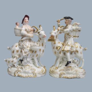 A pair of Bloor Derby white and gilt figures of a tailor and his wife with there three children, both astride Goats, Circa 1820-30