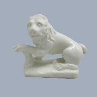 A rare Bow early "Blanc De Chine" seated Lion, left facing on an irregular rock work oblong base with it's left paw resting on a stump. Circa 1750