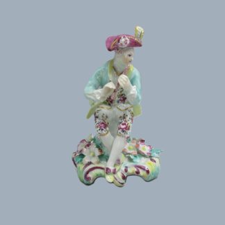 A Derby seated musician playing a flute hand decorated with a turquoise jacket and floral waistcoat and trousers.  Circa 1756
