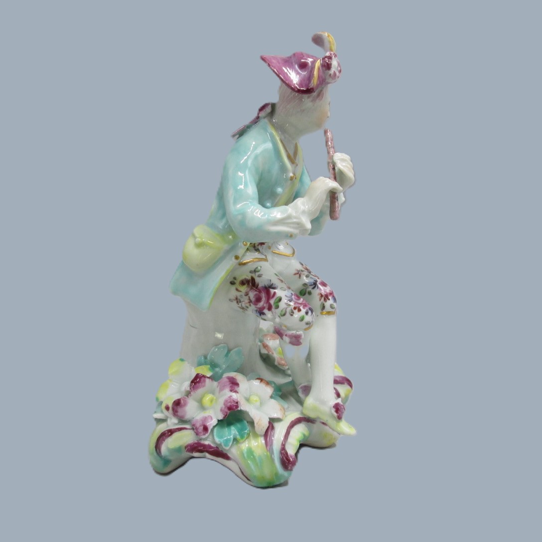 A Derby seated musician playing a flute hand decorated with a turquoise jacket and floral waistcoat and trousers. Circa 1756 - Image 7