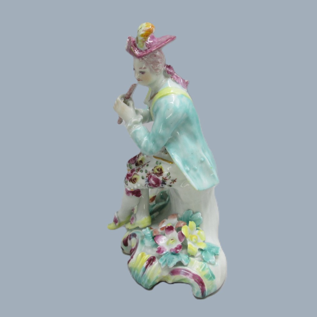 A Derby seated musician playing a flute hand decorated with a turquoise jacket and floral waistcoat and trousers. Circa 1756 - Image 4
