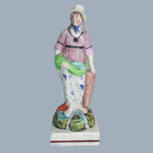 A Staffordshire pearlware square based pottery figure of a Lady holding fish in her apron, emblematic of the element 'Water'. Circa; 1800